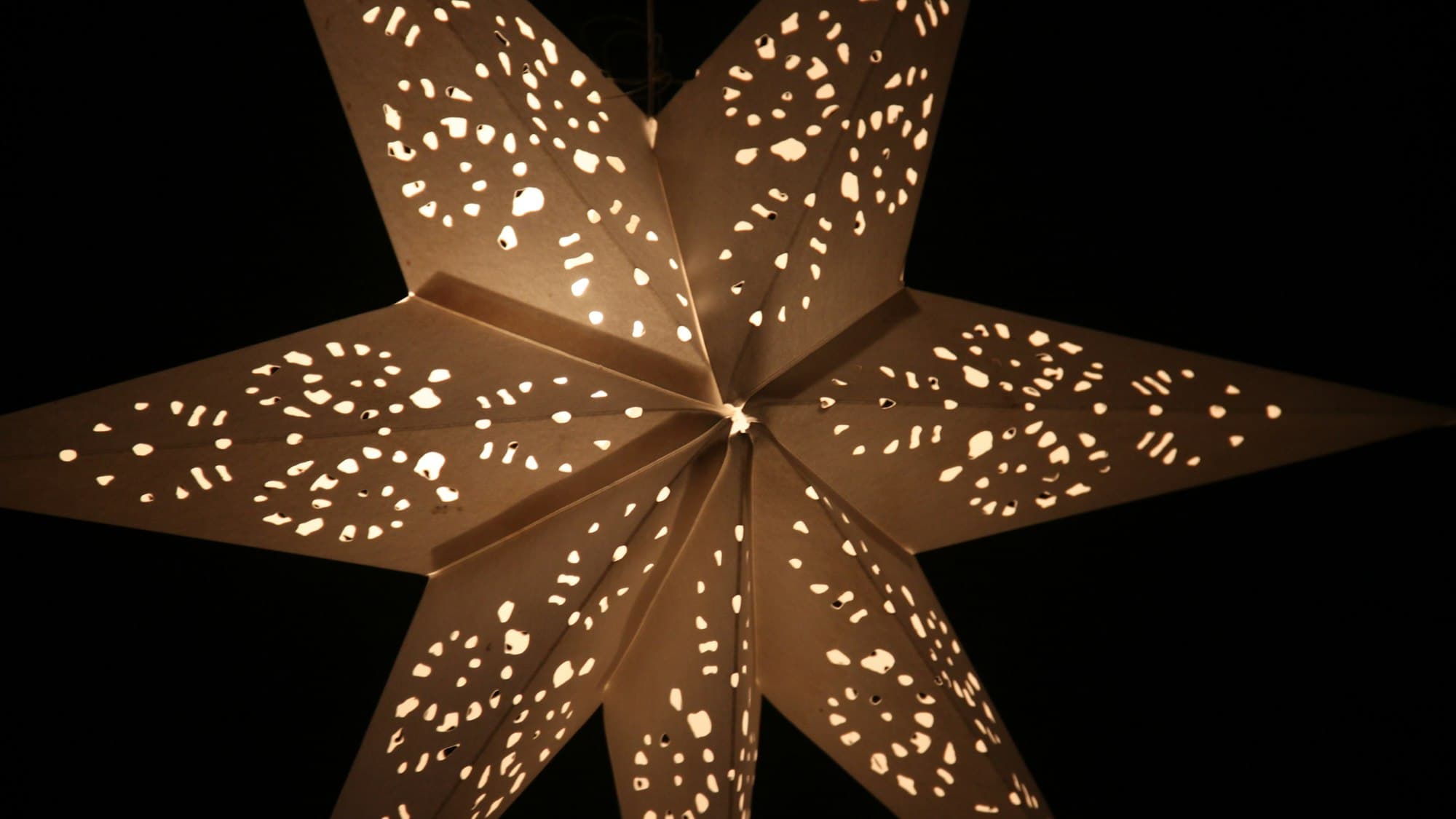 A glowing multi-pointed paper star lantern lit up at night, India's signature Christmas decoration
