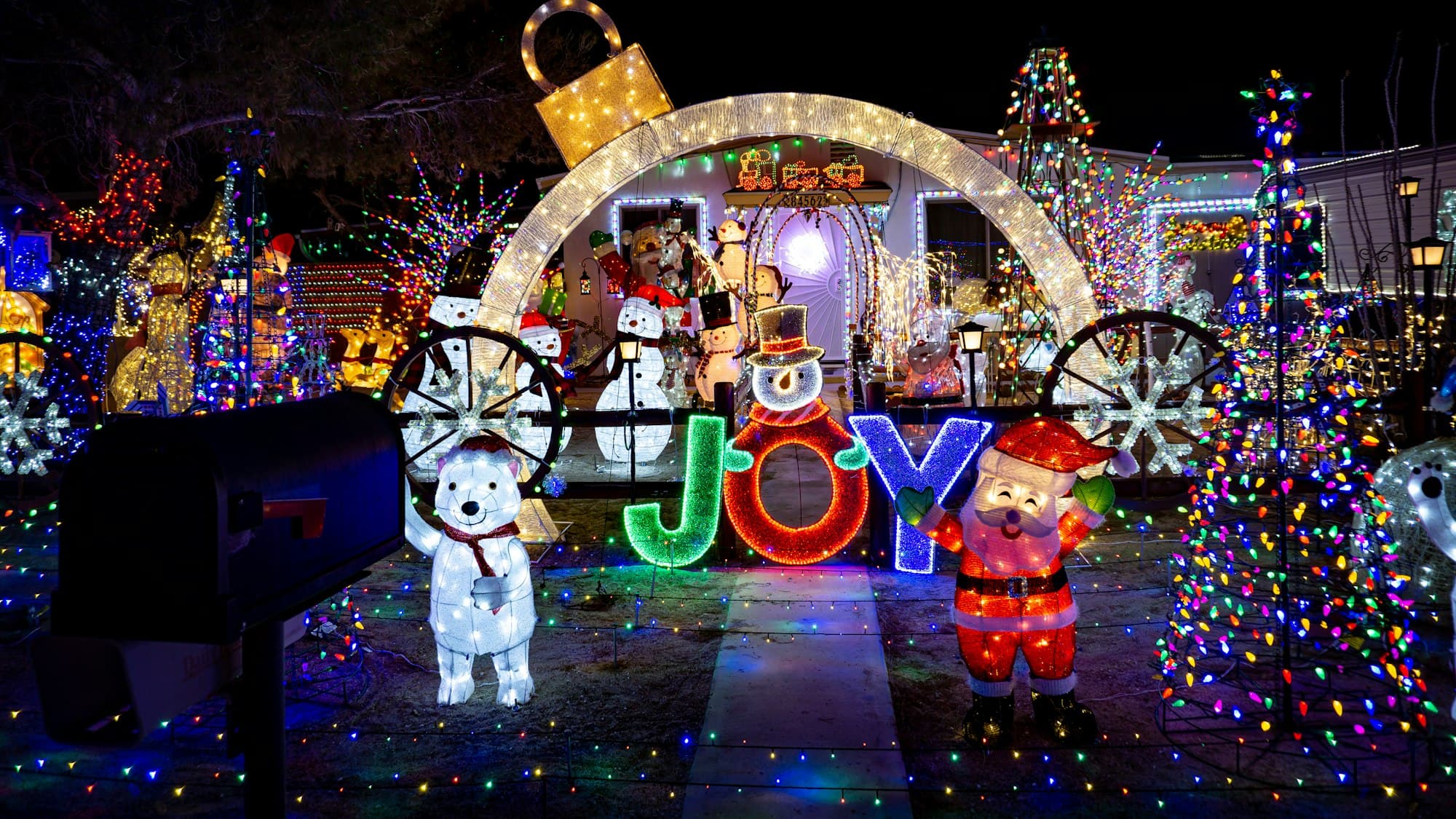 A suburban American house covered in Christmas lights and decorations glowing at night
