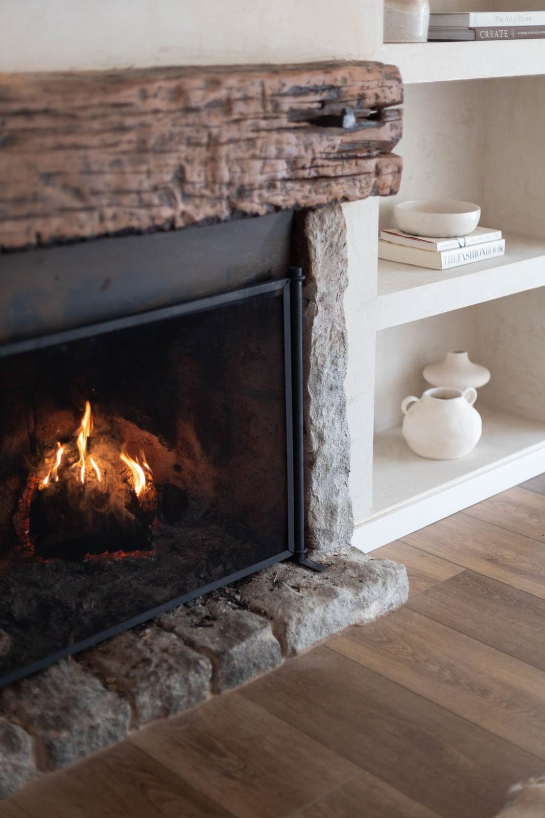 A rustic stone fireplace with a reclaimed-wood beam mantel, undecorated