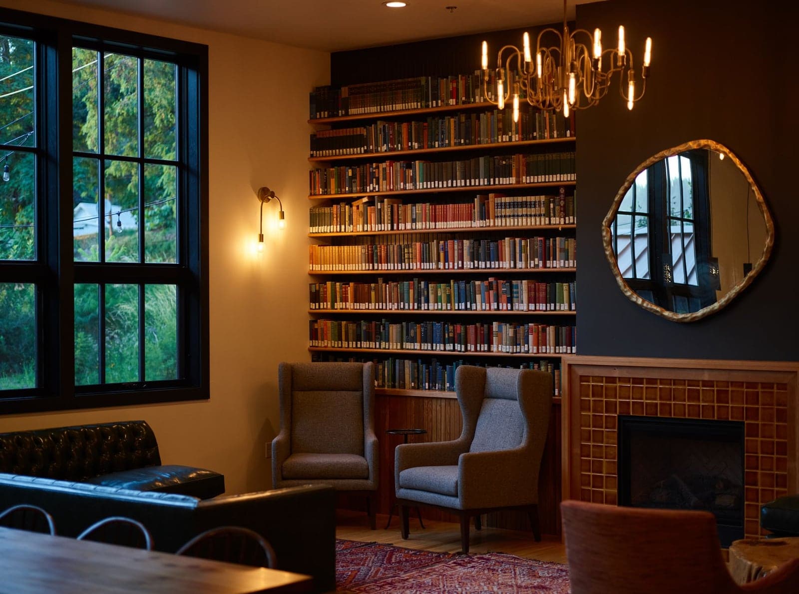 A moody library with full bookshelves and a tiled fireplace, undecorated