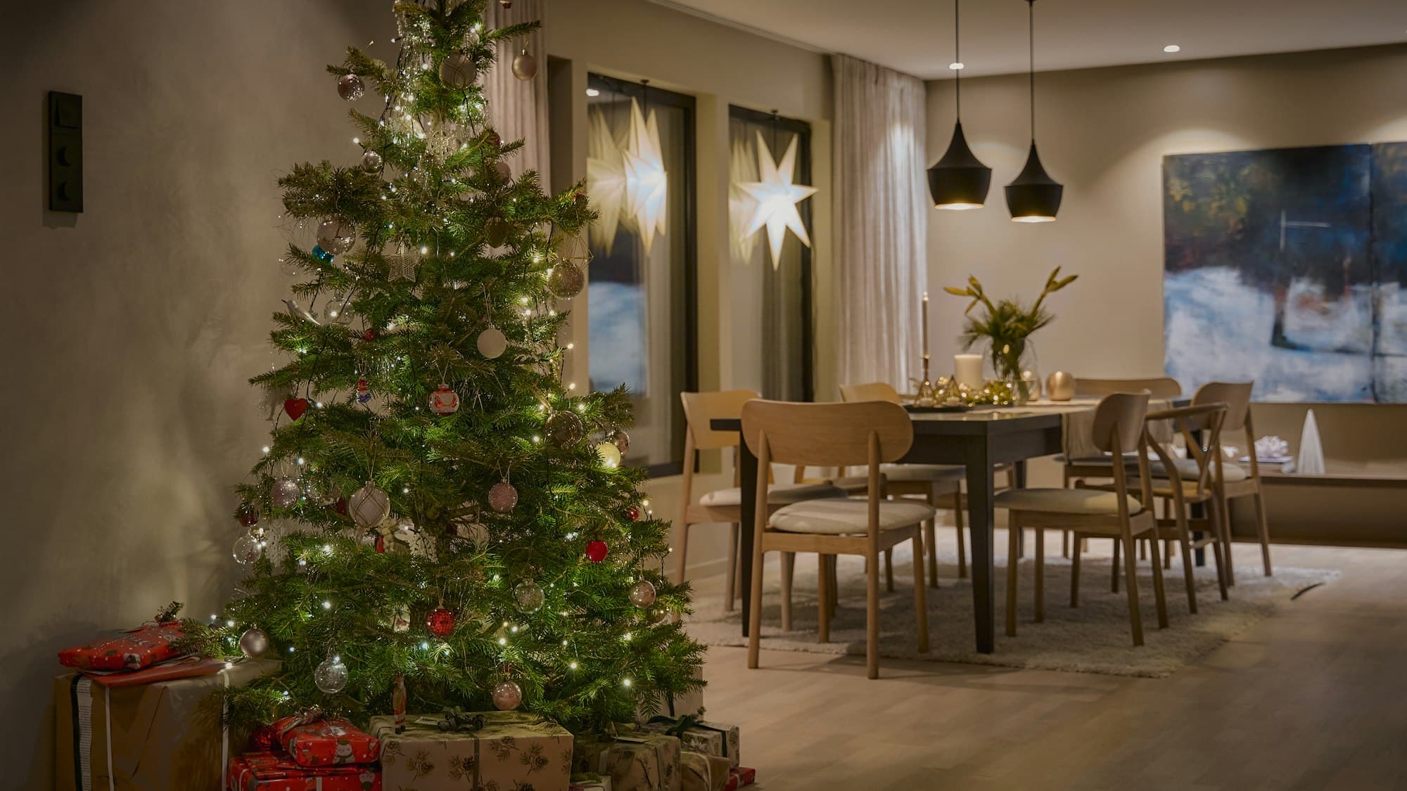 A fully decorated Christmas tree with warm lights in a styled living room at night