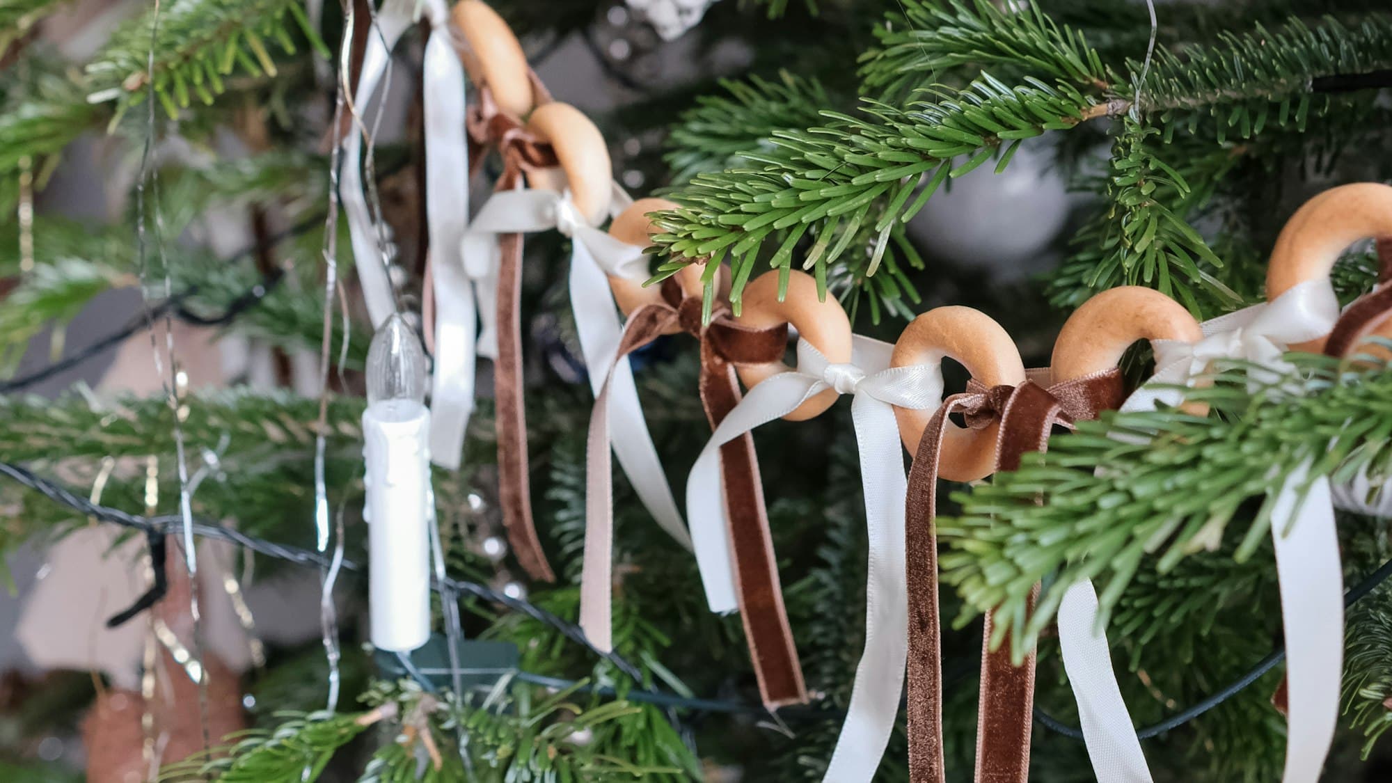 A Christmas tree decorated with handmade natural ornaments (dried orange slices, pinecones, and warm lights) in candlelight