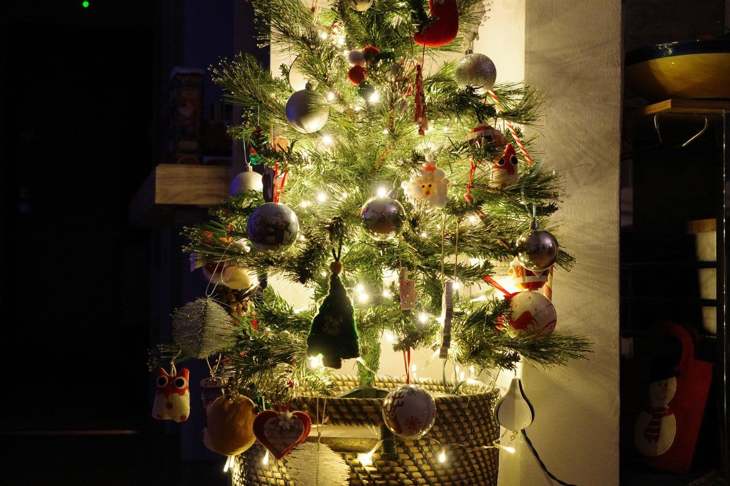 A traditionally decorated Christmas tree glowing with warm string lights and mixed ornaments in a home at night