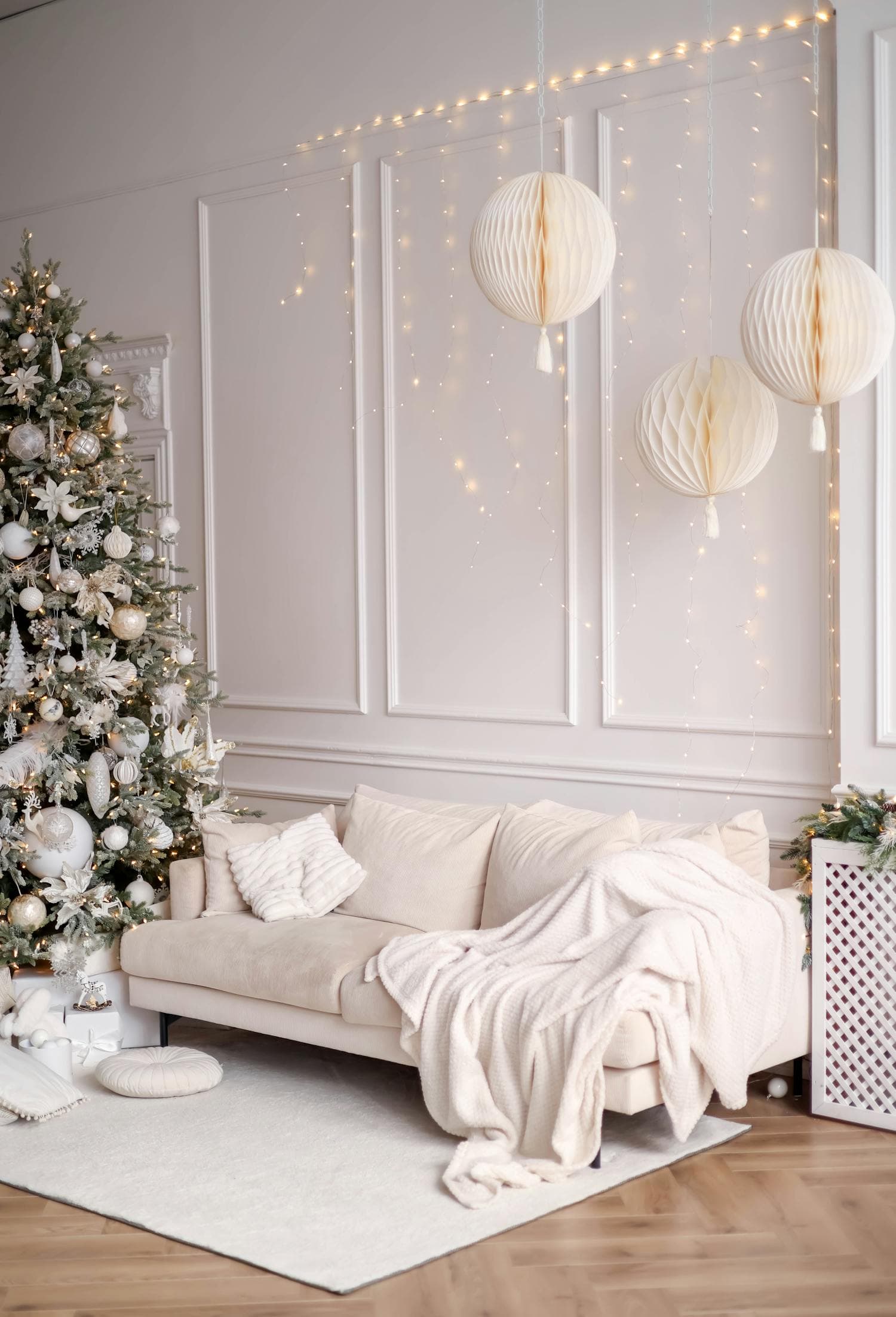 An elegant holiday living room in modern farmhouse style with a flocked white Christmas tree, neutral palette, soft warm lighting, a cozy sofa, and wrapped gifts beneath the tree, the kind of restrained holiday scene that fits white-on-white farmhouse interiors